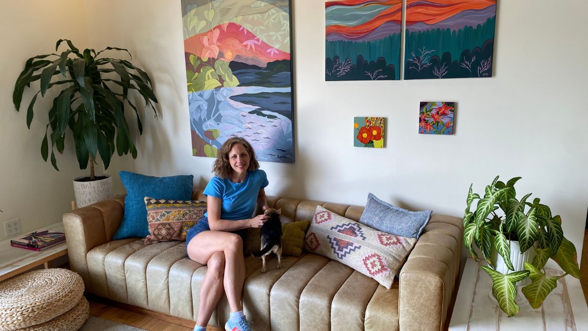 photo of a woman sitting on a couch in front of art work
